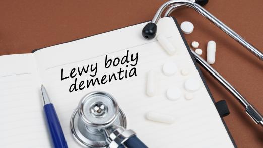 On a brown surface lie pills, a pen, a stethoscope and a notebook with the inscription - Lewy body dementia